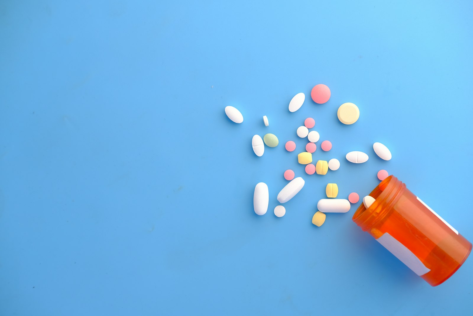 Pills spilling from an orange prescription bottle